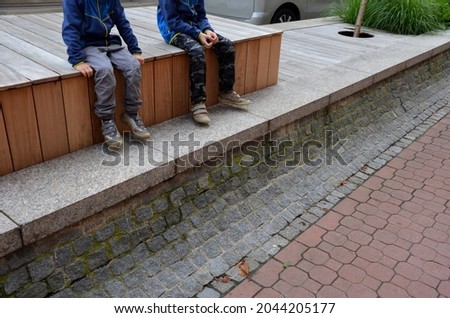 on the edge of the elevated terrace overlooking the park is a concrete long flowerpot with wood paneling and a rectangular bench. is part of the city promenade on the street and square
