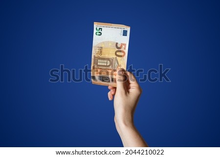  Hand holding a 50 Euro bill isolated on blue background. High quality photo
