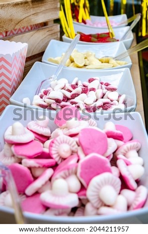 Bowls of pink, white and red sweets make up pic n mix for people to help themselves to at a party.