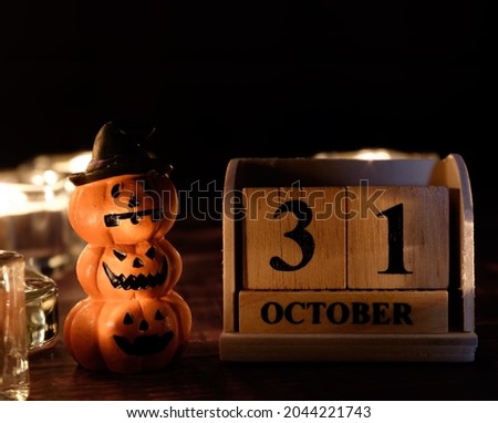 October 31 text on wooden block calendar and pumpkin dolls on wooden background with burning candle.Happy Halloween concept.