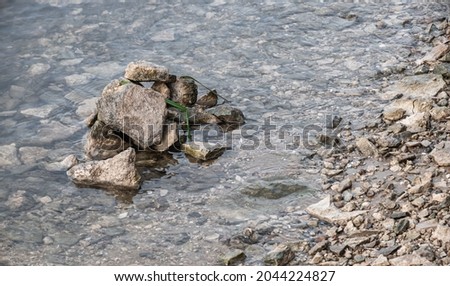 A pile of stones at the riverside. Transparent water with reflections and rocky banks. Rural landscapes by the water.
