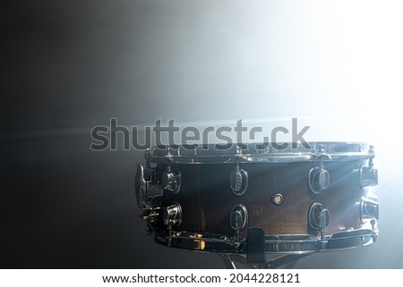 Snare drum, percussion instrument against the backdrop of a bright stage spotlight.