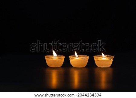 Candle lighting. Shallow depth of field. Numerous Christmas candles light up at night. abstract candle background Numerous candle flames shine on a dark background. Close-up. Empty space.
