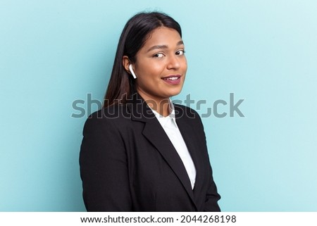 Young Venezuelan business woman isolated on blue background looks aside smiling, cheerful and pleasant.
