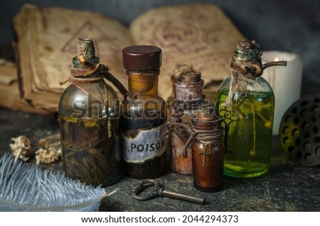 Magic potions in bottles, ancient books and witchery herbs on wooden background, Halloween theme Royalty-Free Stock Photo #2044294373