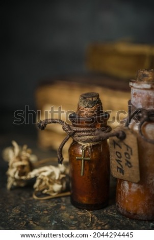 Magic potions in bottles, ancient books and witchery herbs on wooden background, Halloween theme Royalty-Free Stock Photo #2044294445