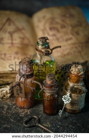 Magic potions in bottles, ancient books and witchery herbs on wooden background, Halloween theme Royalty-Free Stock Photo #2044294454