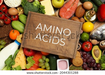 Wooden board with text AMINO ACIDS among different products, top view  Royalty-Free Stock Photo #2044301288