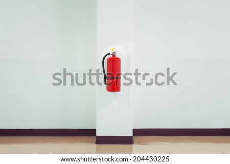 Fire extinguisher hang on office wall. That fire protection device or cylindrical pressure vessel contain dry chemical powder for safety, extinguish or control fire disaster in emergency situation.