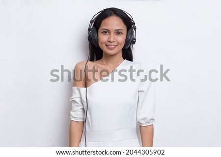 Beautiful young asian woman listening to music isolated on white background
