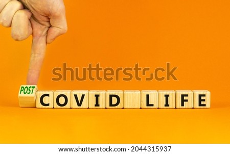 Symbol for a post-covid life. Businessman turns a cube and changes words 'covid life' to 'post-covid life'. Beautiful orange background. Medical, business and covid-19 pandemic concept, copy space.