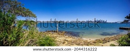 Sunny Spring day on Sydney Harbour with nice rocks in the foreground the soft waves crashing on the shore and the beautiful harbour foreshore as a backdrop NSW Australia