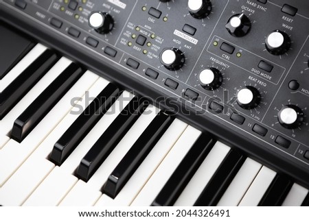 Professional synthesizer piano keyboard and volume regulators. Modern analog synth for electronic music production in sound recording studio  Royalty-Free Stock Photo #2044326491