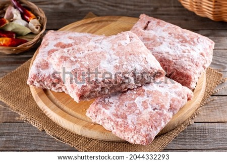 Frozen ground meat, minced pork on a wooden board. Ground chicken inclusive backs, necks, liver and heart. Frozen food. Concept for raw food diet for cats, dogs and pets. Food storage