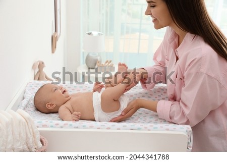Mother changing her baby's diaper on table at home Royalty-Free Stock Photo #2044341788