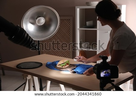 Young woman creating composition with sandwich in studio. Food photography