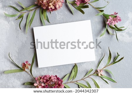 Invitation or greeting card mockup with eucalyptus and hydrangea twigs. Empty card mockup on grey background.