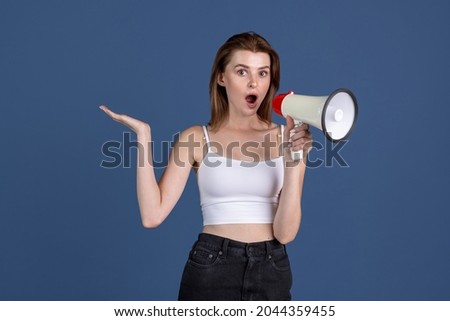 Shouting at megaphone. Traditional portrait of young girl isolated on old navy color studio background. Concept of human emotions, facial expression, beauty, fashion, youth, sales. Copy space for ad