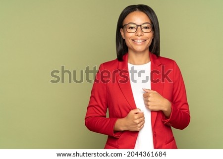 Happy confident african american businesswoman, successful entrepreneur or small business owner female cheerful smiling and looking in camera. Black woman in eyeglasses and red jacket over studio wall Royalty-Free Stock Photo #2044361684
