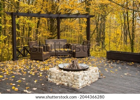 Cozy Autumn patio with chairs, hearth and firewoods.Exterior in backyard for relax in autumn garden. Fall decor. Selective focus.