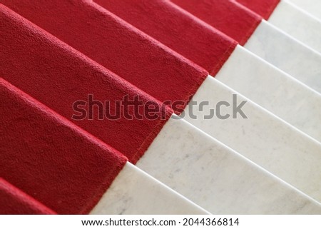 Red carpet is on a white marble stairway going down, top view, abstract background photo texture