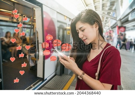 Asian woman passenger using mobile phone to check social network application with number of Like, Love, comment, people and fovorite icon in the Skytrain rails or subway in city, Social media concept