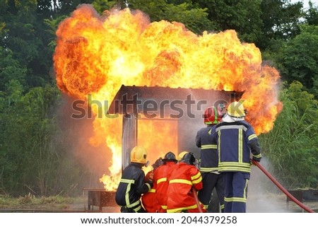 Firefighters using Twirl water fog type fire extinguisher to fighting with the fire flame from oil to control fire not to spreading out. Firefighter and industrial safety concept.                   