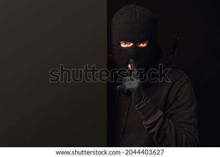 Robber making silence gesture on black