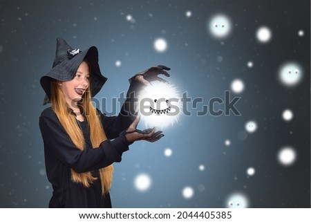 A girl dressed as a witch with a smile creates big-eyed and toothy shaggy monsters. Background for Halloween. Fantastic animals. Holiday illustration