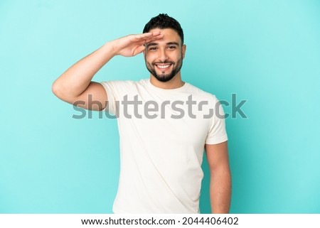 Young arab man isolated on blue background saluting with hand with happy expression Royalty-Free Stock Photo #2044406402