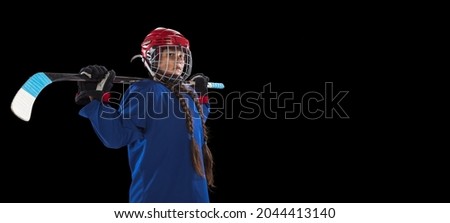 After game. Portrait of child girl hockey player in blue uniform standing with stick isolted over black background. Team spirit, winner goals. Concept of competition, childhood, sport, ad