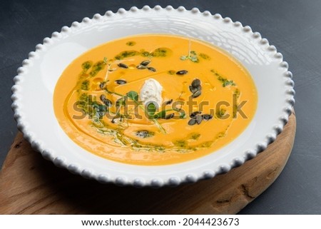 Pumpkin soup in a plate on a gray background. Selective focus.