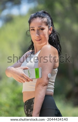 Diabetic woman demonstrating glucose monitoring and checking with remote sensor and smartphone Royalty-Free Stock Photo #2044434140