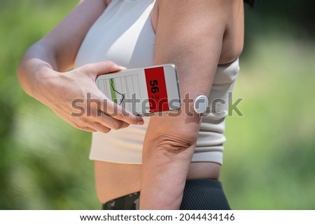 Diabetic woman monitoring and checking glucose level with a remote sensor and a new technology with an app in smartphone Royalty-Free Stock Photo #2044434146