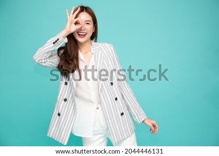 Asian business woman smiling and showing OK sign isolated on green background