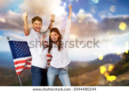 Young happy family with the American flag behind them celebrates Independence Day.