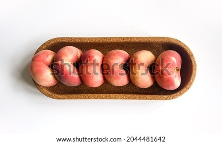 Six, fresh, ripe, flat donut peaches, saturn peaches, in a cork tray. Isolated on white background, text space. Flat lay, top view. Fresh organic vegan fruit. Harvest concept. Summer fruit background.