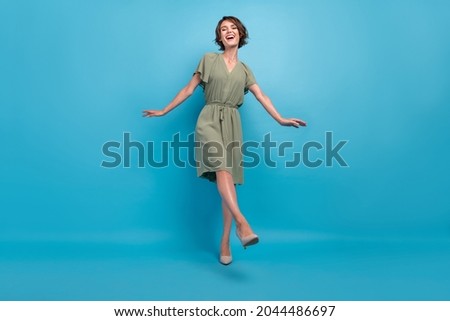 Full size photo of cute young brunette lady dance wear khaki dress stilettos isolated on blue background