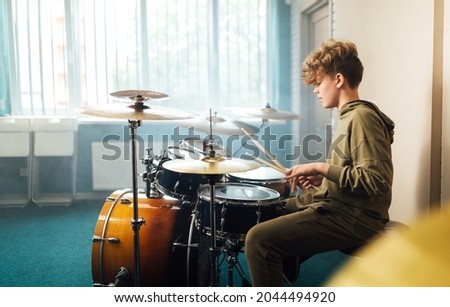 Boy musician behind a drum kit. Royalty-Free Stock Photo #2044494920