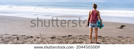 Panoramic photo of a woman on her back on a deserted beach looking at the sea