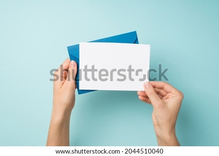 First person top view photo of hands holding blue envelope and white card on isolated pastel blue background with empty space Royalty-Free Stock Photo #2044510040
