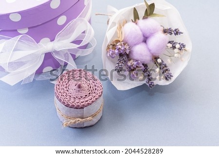 Natural wax candle for interior, small bouquet of dried flowers and gift box on blue background. Handmade eco gift. Close up