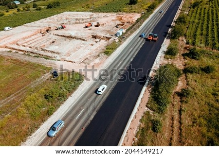Aerial top view of roadworks with road workers lay asphalt. Work on laying of asphalt. Aerial photography. The repair of the road. The view from the top