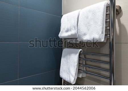 White towels are dried on a heated towel rail in the bathroom Royalty-Free Stock Photo #2044562006