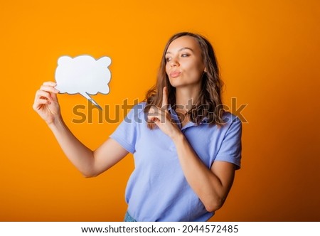 Happy young woman holding empty speech bubble on yellow background.