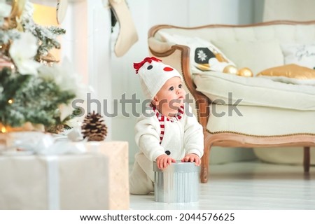 Baby in snowman costume crawls on background of Christmas tree. Infancy, babyhood at home at New Year. Baby's First Christmas