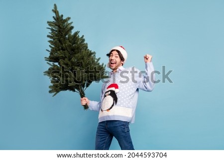 Photo of positive cheerful happy man winner hold hand christmas green tree isolated on blue color background