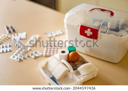 Closeup female hand neatly placing medicament at domestic first aid kit top view. Storage organization in transparent plastic box drug, pill, syringe, bandage. Fast health help safety emergency supply Royalty-Free Stock Photo #2044597436