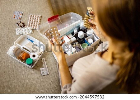 Closeup female hand neatly placing medicament at domestic first aid kit top view. Storage organization in transparent plastic box drug, pill, syringe, bandage. Fast health help safety emergency supply Royalty-Free Stock Photo #2044597532
