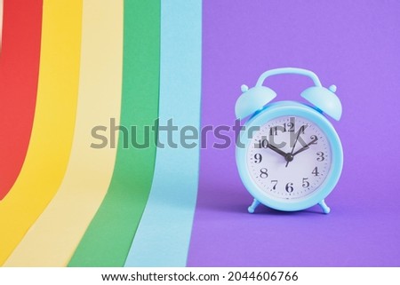 Blue alarm clock on colorul rainbow background copy space